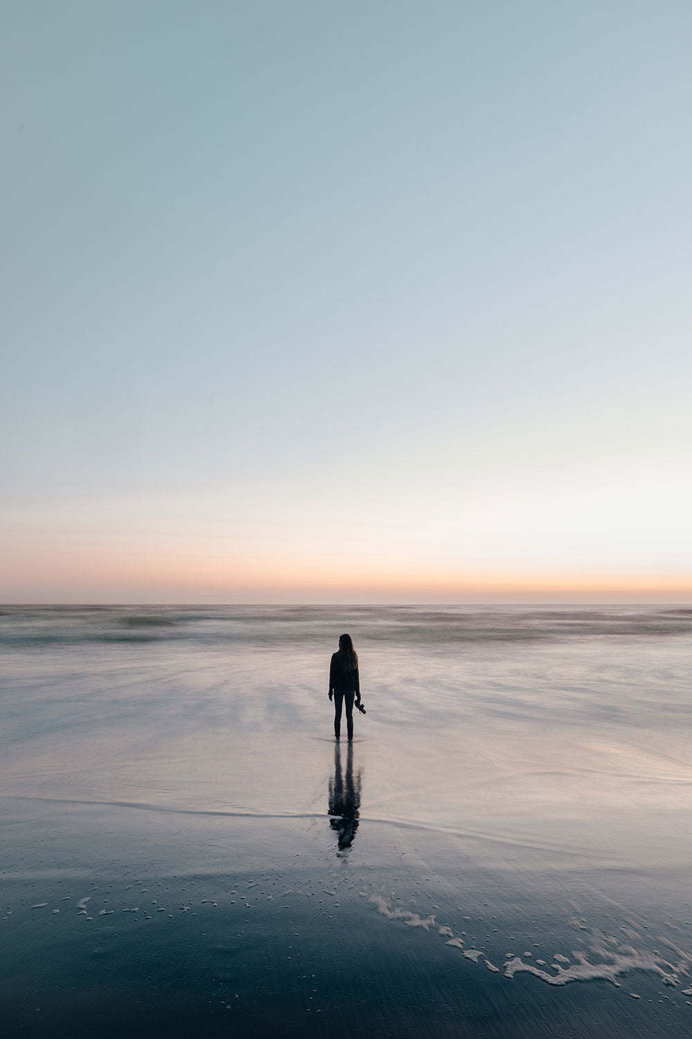 online life coach wades in ocean at sunset